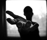 Silhouette of a hand reaching out in a black and white contrast.